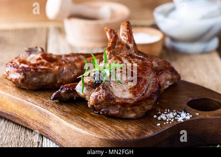 Côtelettes de veau grillées aux herbes fraîches sur planche à découper en bois rustique, pan steak poêlé Banque D'Images