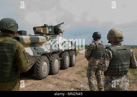 L'entraîneur d'observateurs ukrainiens, ainsi que des formateurs avec un mentor de la Lituanie, regardent les soldats du 1er Bataillon de l'Ukraine, 95e brigade aéromobile conduite séparée monté et démonté combiné formation techniques de mouvement en utilisant leur véhicule blindé BTR-3 au Centre de formation de combat de Yavoriv sur le maintien de la paix internationale et la sécurité près de l'viv, l'Ukraine le 21 août. (Photo de 1er lieutenant Kayla Christopher, 45th Infantry Brigade Combat Team) Banque D'Images