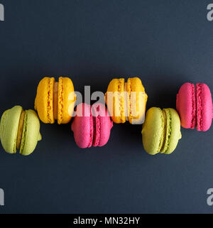 Rangée de gâteaux macarons multicolores sur fond noir, copy space Banque D'Images