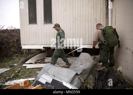 2 agents de patrouille frontalière à pied autour d'une maison mobile endommagé au cours de la réalisation des opérations de recherche et sauvetage dans le sillage de l'ouragan Harvey le 27 août, 2017. U.S. Customs and Border Protection photo par Glenn Fawcett Banque D'Images