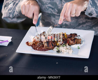 Le colonel Bradley McDonald, 88e Escadre, Base aérienne de brochettes d'échantillons faites par le sergent-chef. Jacob Hellickson, 124e escadron du Renseignement du Bureau de l'Inspecteur général, dans l'appréciation de la salle ronde Madness concours culinaire organisé par l'USO 22 août 2017, à Wright-Patterson Air Force Base, Ohio. McDonald et les autres juges, y compris le célèbre chef Robert Irvine, décerné Hellickson première place dans la compétition. (U.S. Photo de l'Armée de l'air par R.J. Oriez) Banque D'Images