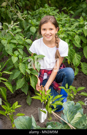 Happy smiling girl travaillant dans coupe de terre de jardin Banque D'Images