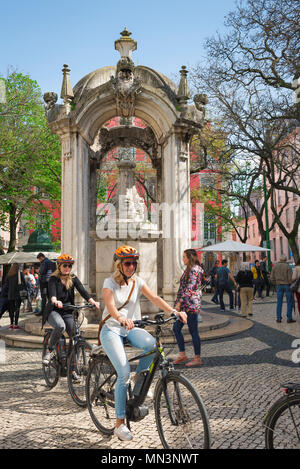 Place de Lisbonne, vue sur un après-midi de printemps de deux femmes à vélo à travers le Largo do Carmo dans le quartier Bairro Alto de Lisbonne, Portugal. Banque D'Images