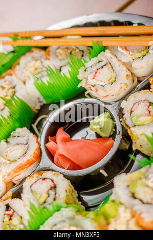 Close up of selective focus de grand ensemble de délicieux rouleaux de sushi japonais sur une plaque en plastique noir Banque D'Images