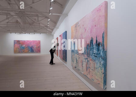 Londres, Royaume-Uni. 14 mai 2018. Un membre du personnel des oeuvres de l'artiste vue Franco-iranienne Sassan Behman Bakhtiar, à un aperçu de l'exposition de l'artiste appelé 'Unité' de bien-être, à la Saatchi Gallery à Chelsea. Les œuvres colorées s'appuyer sur des milliers d'années de la culture iranienne, le tissage de motifs de la Perse ancienne, de motifs et de paysages dans les grandes peintures technique mixte, rappelant les montagnes de Zagros au sud-ouest de l'Iran, toujours le foyer de la tribu Bakhtiari, à partir de laquelle l'artiste est descendu. Le spectacle s'exécute 15 au 27 mai 2018. Crédit : Stephen Chung / Alamy Live News Banque D'Images