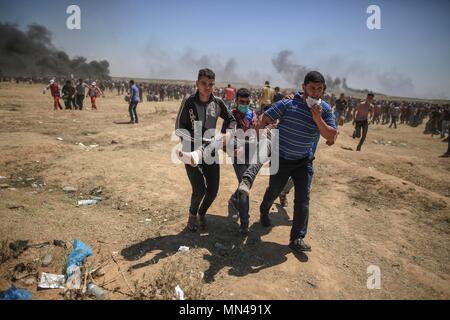 (180514) -- Gaza, 14 mai 2018 (Xinhua) -- des manifestants palestiniens transportent un homme blessé lors d'affrontements avec des soldats israéliens près de la frontière Gaza-Israel, est de la ville de Gaza, le 14 mai 2018. Plus de 40 Palestiniens, dont des enfants, ont été tués lundi lors d'une journée de violents affrontements avec les forces israéliennes sur la frontière sud d'Israël avec Gaza, selon le ministère de la santé de Gaza. (Xinhua/Wissam Nassar) Banque D'Images