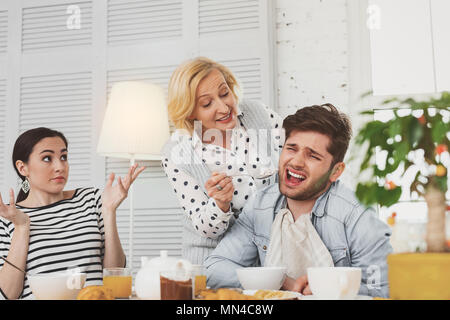 Belle femme âgée essayer de nourrir son fils Banque D'Images