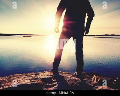 Silhouette d'homme debout sur un rocher et à plus de mer vers le soleil du soir. Coucher du soleil à l'cooastline Banque D'Images