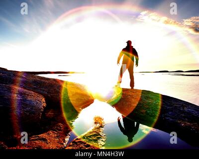Silhouette d'homme debout sur un rocher et à plus de mer vers le soleil du soir. Coucher du soleil à l'cooastline Banque D'Images
