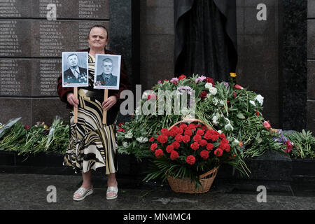 Une femme est titulaire d'une photo de personnes qui ont combattu pendant la Seconde Guerre mondiale au cours de la Journée de la victoire le 9 mai qui commémore la victoire de l'Union soviétique sur l'Allemagne nazie dans le Mémorial de la gloire un monument commémorant les anciens combattants et les morts de la Grande Guerre patriotique (Seconde Guerre mondiale), la guerre soviéto-afghane, et de la guerre de Transnistrie 1990-1992 situé sur place Souvorov Tiraspol dans la capitale et le centre administratif de l'intérieur des frontières internationalement reconnues de la Moldova dans le cadre d'un contrôle de fait de la République moldave Pridnestrovian aussi appelée la Transnistrie (PMR) depuis 1992. Banque D'Images