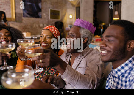 Multi-generation family wearing Christmas paper crown, toasting champagne Banque D'Images