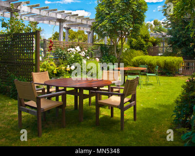 Jardin aménagé avec table à manger en bois situé à l'ombre des arbres Banque D'Images