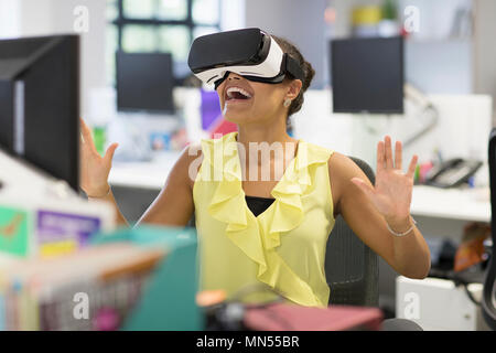 Femme d'enthousiaste à l'aide du simulateur de réalité virtuelle lunettes dans office Banque D'Images