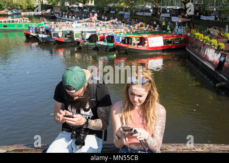 Un couple tatoué absorbée dans des messages sur les rives du Grand Union Canal dans la Petite Venise, Londres, UK Banque D'Images