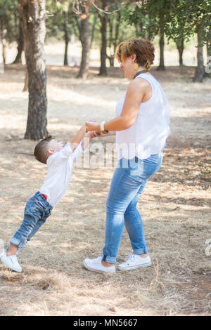 Mother swinging fils par des mains dans le parc Banque D'Images