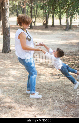 Mother swinging fils par des mains dans le parc Banque D'Images