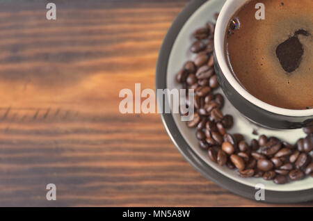 Un bol vert avec du café sur une soucoupe avec café en grains Banque D'Images