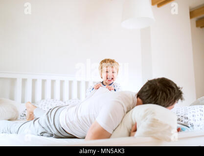 Père mature avec un bébé garçon s'amuser dans la chambre à la maison au coucher. Le congé de paternité. Banque D'Images