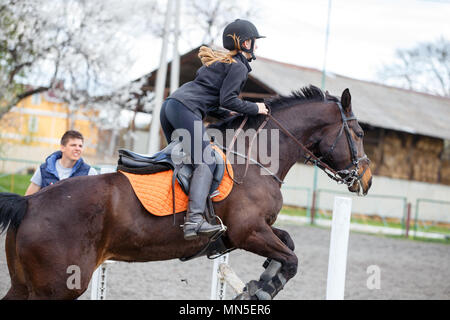 Jeune fille sur bay saut à cheval en saut d'obstacle sur la formation Banque D'Images