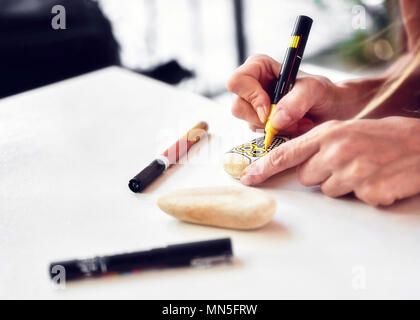 Caucasian woman painting un hibou sur une pierre. La peinture de Pierre passe-temps, les arts et métiers. Banque D'Images