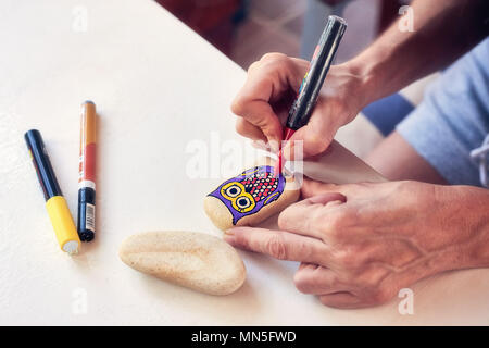 Caucasian woman painting un hibou sur une pierre. La peinture de Pierre passe-temps, les arts et métiers. Banque D'Images