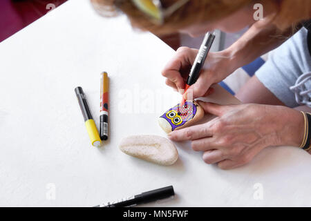 Caucasian woman painting un hibou sur une pierre. La peinture de Pierre passe-temps, les arts et métiers. Banque D'Images