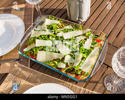 Table extérieure sous le soleil avec de la salade de pâtes plats, verres à vin en cristal et une bouteille de vin blanc frais dans le refroidisseur Banque D'Images