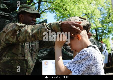 Le sergent de l'armée américaine. Jared Cherry Mettre son casque en Kevlar sur un garçon polonais, Gizycko, Pologne, mai 2018. Image courtoisie de la CPS. Hubert Delany / Battle Group Pologne. () Banque D'Images