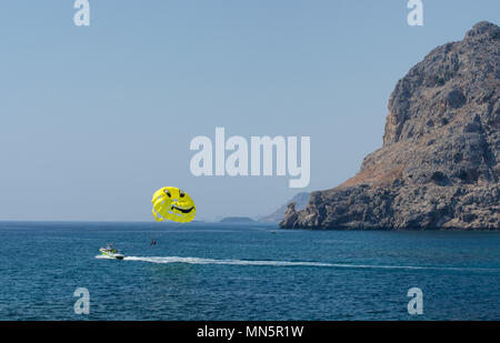 Paysage marin de la Méditerranée avec les touristes engagés dans le parapente. Parachute avec un smiley. Côte près de mont Tsampika (Grèce). Banque D'Images