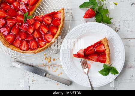 Tarte aux fraises maison décorée de feuilles de fraisier et part dans une assiette. Vue d'en haut Banque D'Images