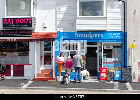 Vieux couple avec deux chiens, l'achat de glaces d'un magasin à bord de route de la jetée de Littlehampton West Sussex England UK Banque D'Images