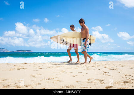 RIO DE JANEIRO - février 08, 2017 : jeune couple brésilien à pied avec des planches le long d'un quartier calme de la plage d'Ipanema Banque D'Images