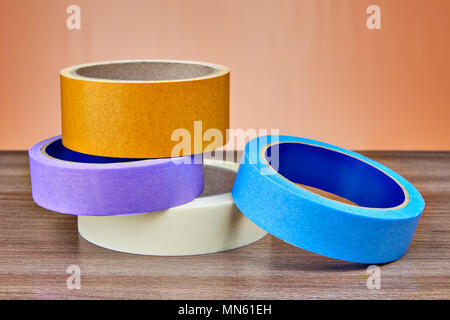 Rouleaux de papier de différentes couleurs et de bande adhésive en plastique se trouvent sur la table. Banque D'Images