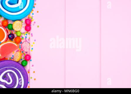 La frontière du côté de l'assortiment de bonbons colorés sur un fond de bois de rose Banque D'Images