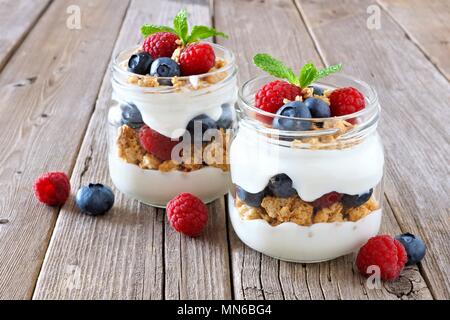 Bleuets sains et framboise les parfaits dans des pots Mason sur un fond de bois rustique Banque D'Images