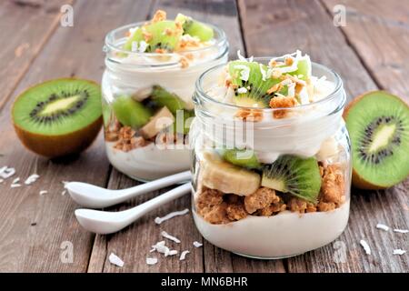 Kiwi Santé, banane, noix de coco les parfaits dans des pots Mason sur un fond de bois rustique Banque D'Images