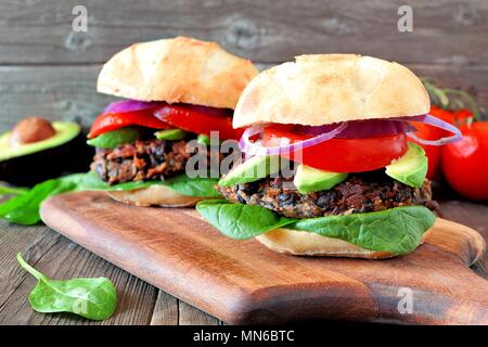 Bean veggie burgers et pommes de terre avec de l'avocat et les épinards dans un fond de bois rustique Banque D'Images