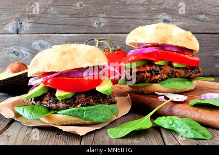 Deux haricots végétariens hamburgers et pommes de terre avec de l'avocat et les épinards dans un fond de bois rustique Banque D'Images