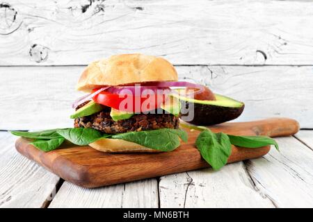 Fève végétarienne et sweet potato burger à l'avocat et les épinards dans un fond de bois blanc rustique Banque D'Images