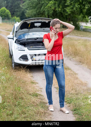 Jeune femme en colère a éclaté dans le domaine automobile et appelant à l'aide Banque D'Images