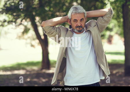 Portrait d'un homme mûr, modèle de la mode, dans un parc urbain. Le plus âgé avec des cheveux blancs et sa barbe portant des vêtements décontractés. Banque D'Images