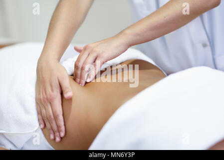 Patiente est sous traitement par des professionnels de l'ostéopathie thérapeute. Femme recevant un massage du ventre au spa salon Banque D'Images