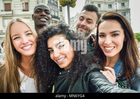 Groupe multiracial d'amis prenant en selfies une rue urbaine avec une femme musulmane en premier plan. Trois jeunes femmes et deux hommes portant des vêtements décontractés. Banque D'Images