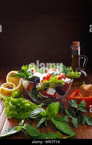 Salade grecque avec de l'huile d'olive dans un bol en verre. Des légumes frais et des herbes. Un endroit pour des inscriptions. Banque D'Images