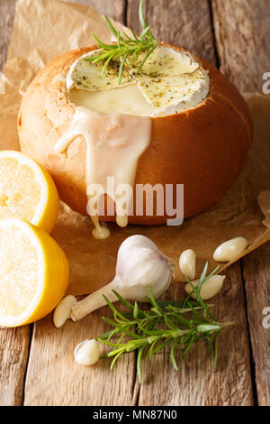 Fondue dans une miche de pain de fromage Camembert fondu sur une table verticale. Banque D'Images