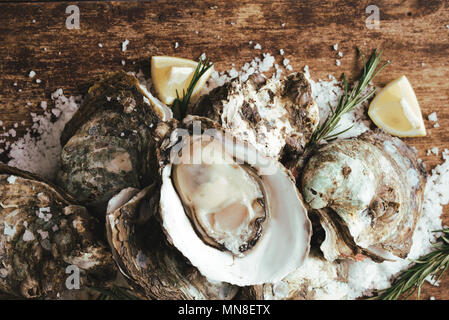 Oyster shell ouvert avec le citron et le sel sur une planche en bois Banque D'Images