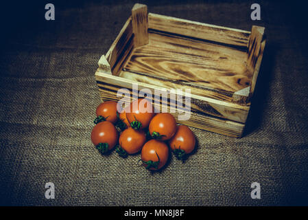 Les tomates fraîches et vieille caisse de bois brûlé ou fort d'un sac vintage rétro arrière-plan.et effet ajouté. Banque D'Images