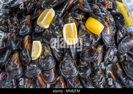 Le style turc apéritif Moules farcies d'aliments de rue appelé midye dolma sur banc de la vente avec le citron qui est servi avec un jet de jus de citron en est Banque D'Images