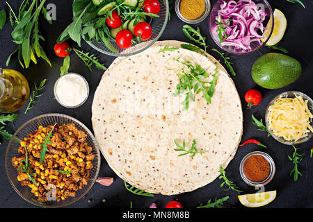 Ingrédients pour les burritos Wraps au boeuf et légumes sur fond noir. Cuisine mexicaine. Vue d'en haut. Mise à plat Banque D'Images