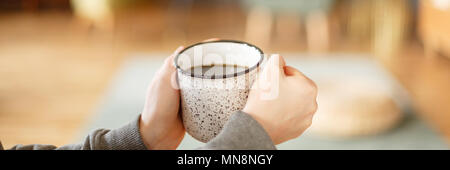 Photo en gros plan de woman's hands holding a white, metal mug avec plateau Banque D'Images